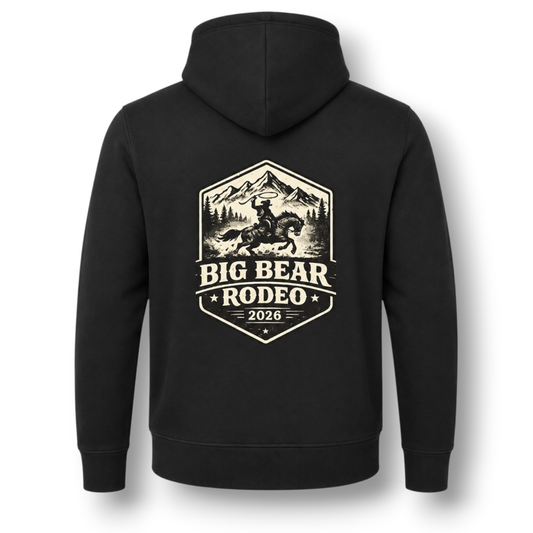 The back of a black hoodie, featuring a large white colored graphic print that reads 'BIG BEAR RODEO 2026' with an illustration of a cowboy on a horse in front of mountains.