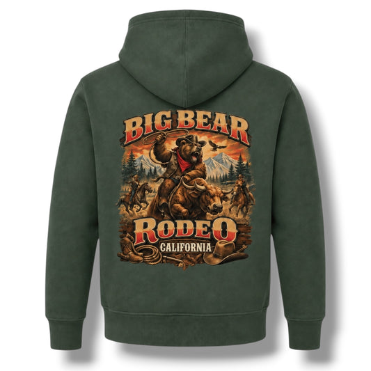 A dark green pullover hoodie shown from the back, featuring a large graphic print of a cowboy riding a bucking bear with the text 'BIG BEAR RODEO 2026' in red and gold lettering.