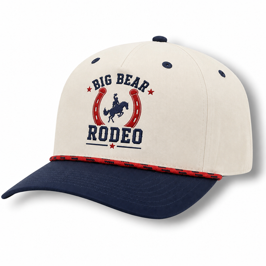 White and navy hat with a horseshoe and Big Bear Rodeo font on a white background