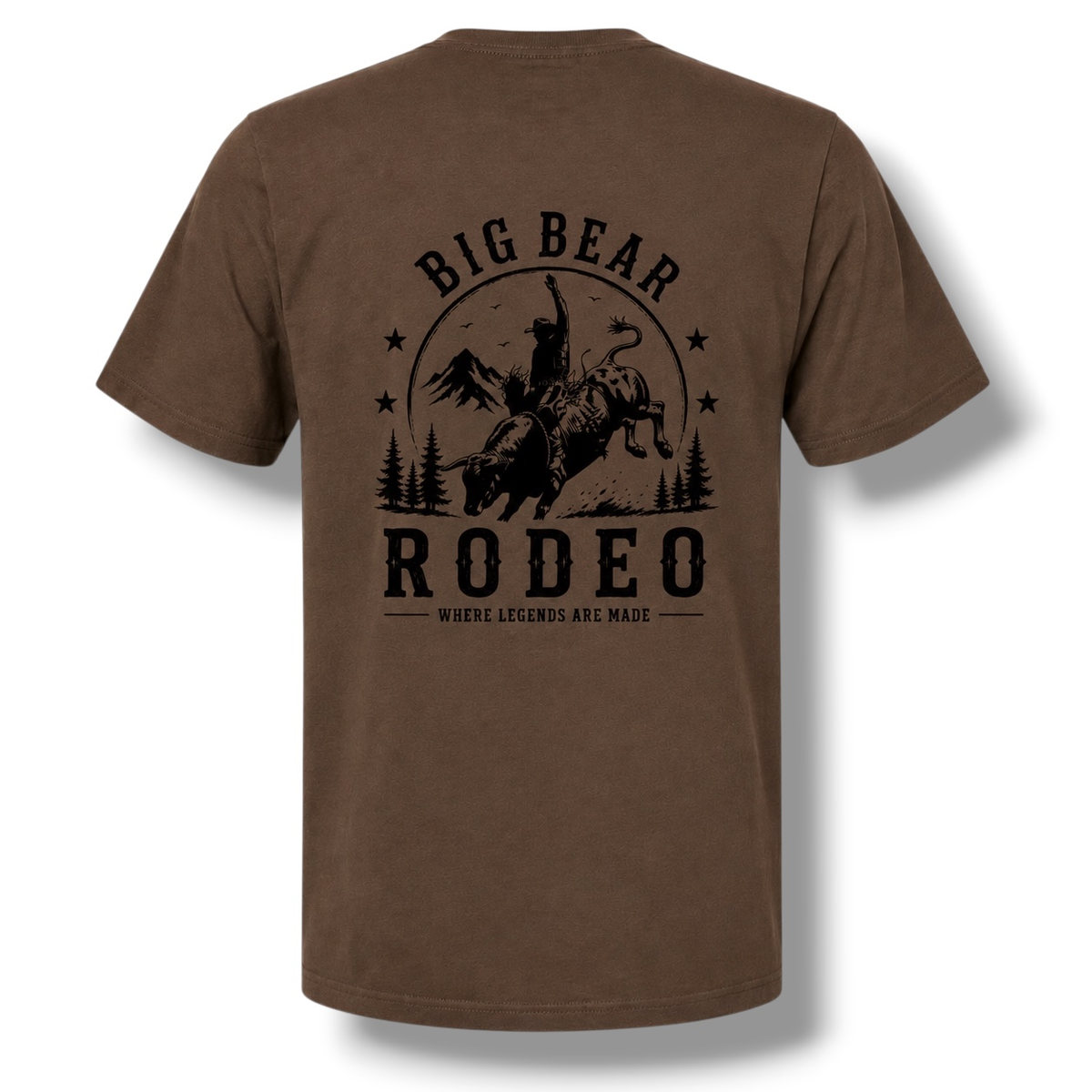 A dark color short-sleeve t-shirt with a black graphic print on the back featuring a cowboy riding a bucking bull in front of mountains and trees, with the text 'BIG BEAR RODEO' and 'WHERE LEGENDS ARE MADE'.