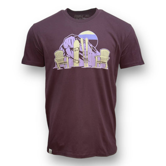 Plum colored t shirt with purple gradient sun and mountain design with a snowboard, skis, and two chairs in light cream color