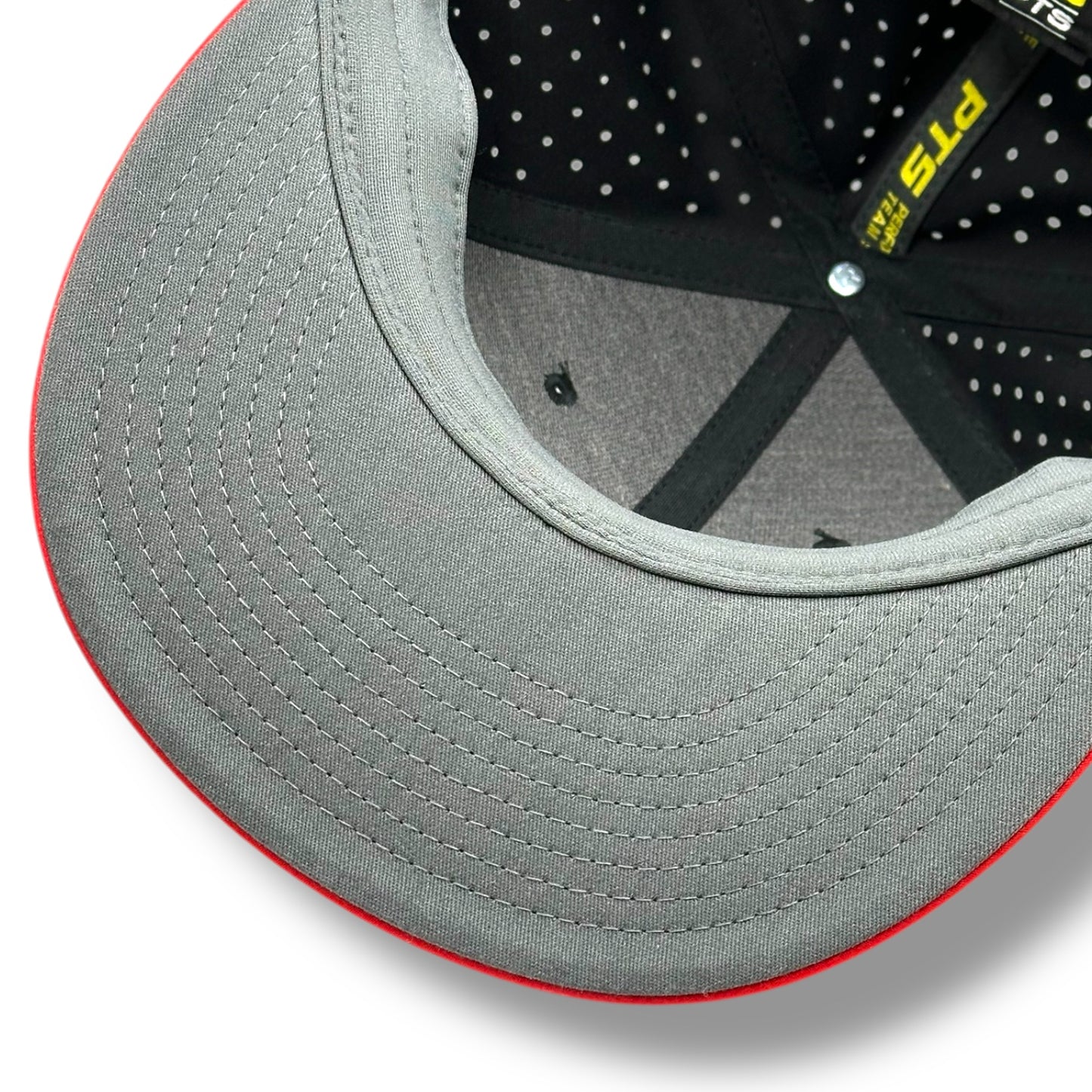 The gray under brim of a black hat, with red brim and gray with black lining and perforations for breathability.