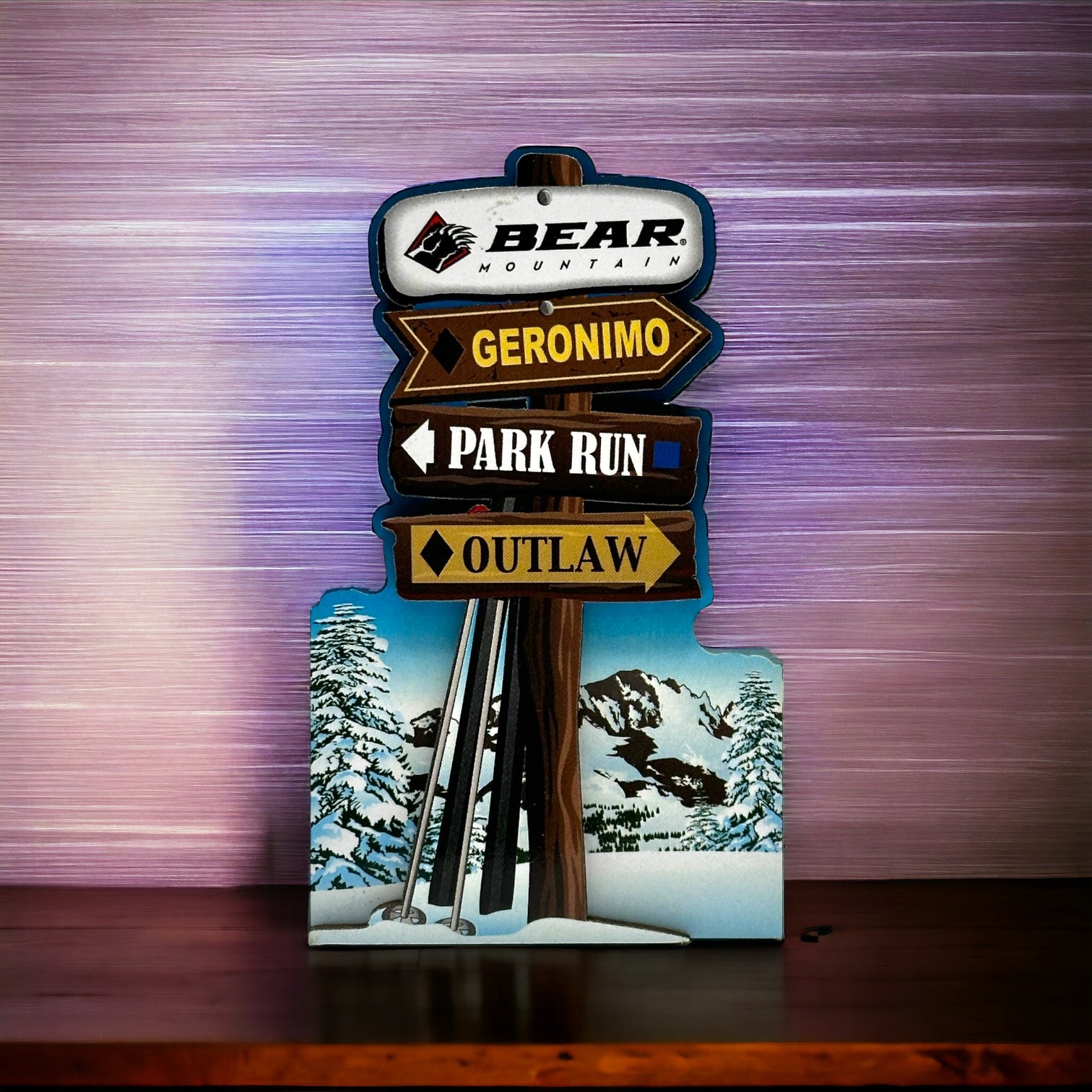 This wooden magnet features a snowy base with skis and ski poles leaning against a wooden post, showcasing the Bear Mountain logo at the top and the three main winter trails below.