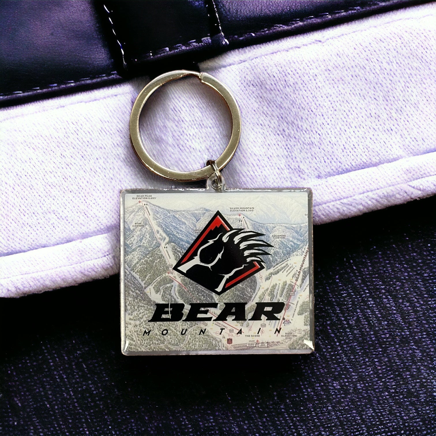 Bear Mountain winter trail maps keychain with trail map in background and bear claw logo in red, black, and white overlay