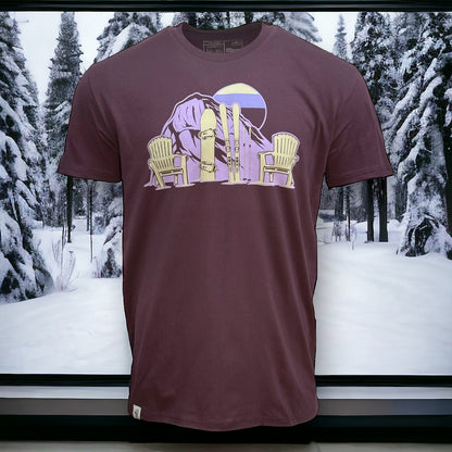 Plum colored t shirt with purple gradient sun and mountain design with a snowboard, skis, and two chairs in light cream color