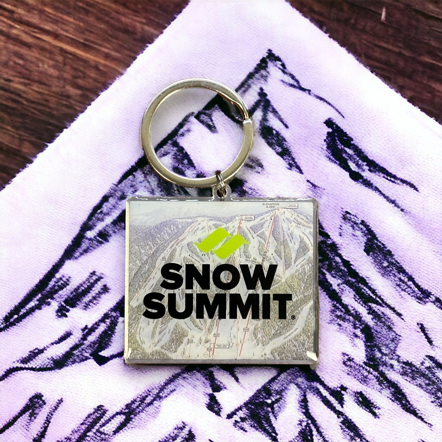 Snow Summit winter trail maps keychain with winter map in background and Snow Summit logo overlay in black and green