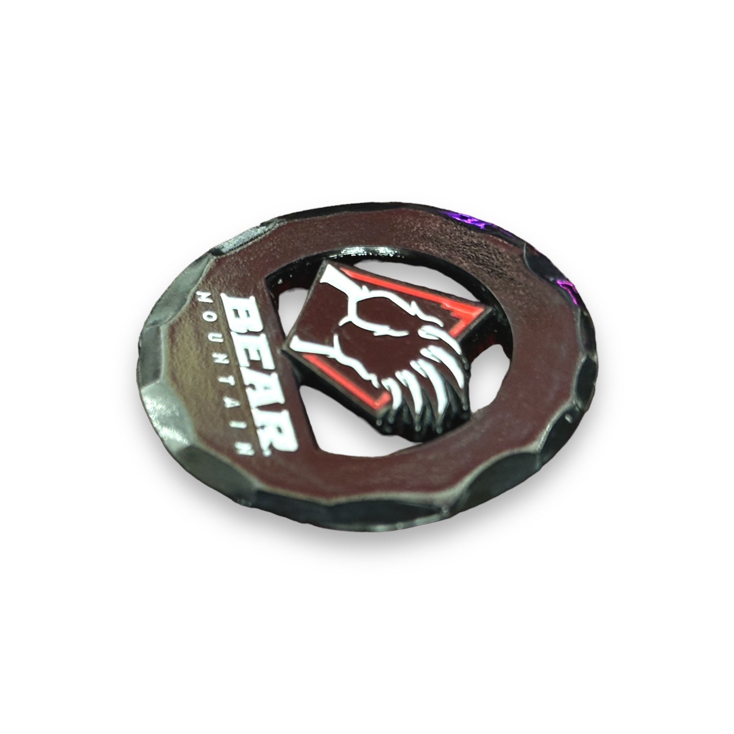 Black circular golf ball market with the Bear Mountain logo with bear claw design in white and red in the middle.