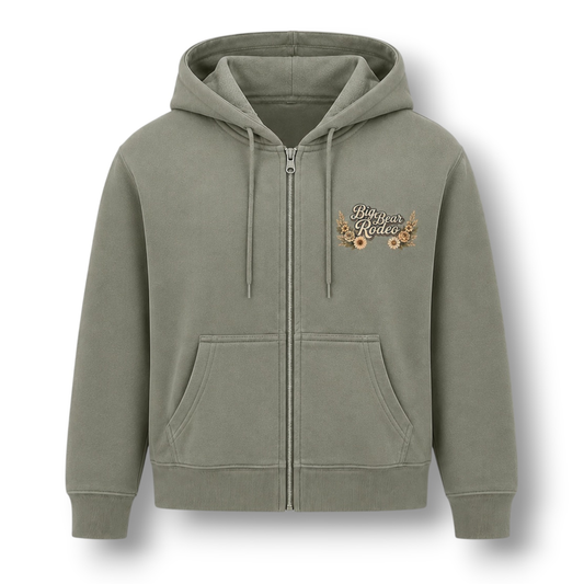 A sage green zip-up hoodie shown from the front. The front features a small 'Big Bear Rodeo' graphic on the left chest surrounded with flowers.