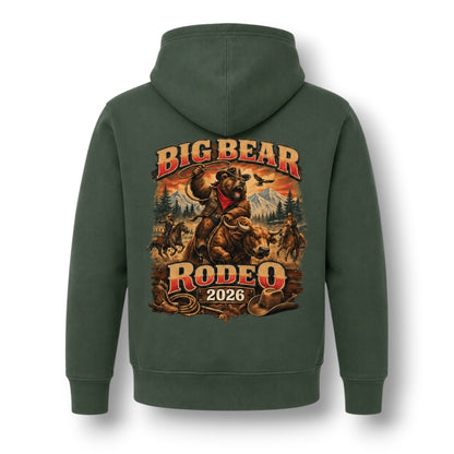 A dark green pullover hoodie shown from the back, featuring a large graphic print of a cowboy riding a bucking bear with the text 'BIG BEAR RODEO 2026' in red and gold lettering.