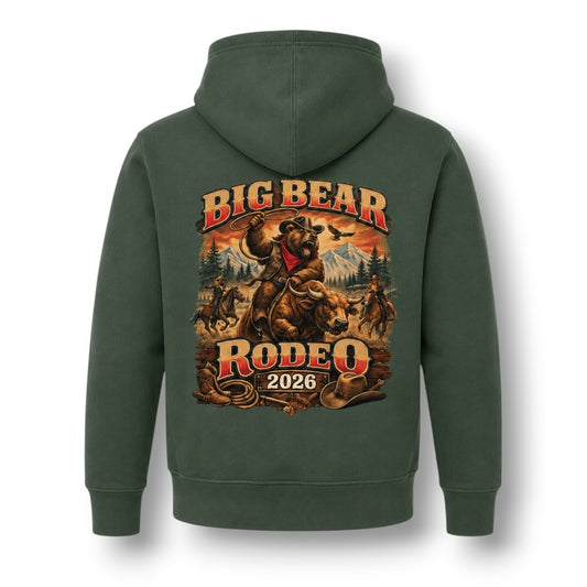 A dark green pullover hoodie shown from the back, featuring a large graphic print of a cowboy riding a bucking bear with the text 'BIG BEAR RODEO 2026' in red and gold lettering.