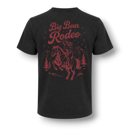 A black short-sleeve t-shirt shown from the back, featuring a dusty red graphic print of a cowboy riding a bucking horse under the words 'Big Bear Rodeo' with mountains and pine trees.
