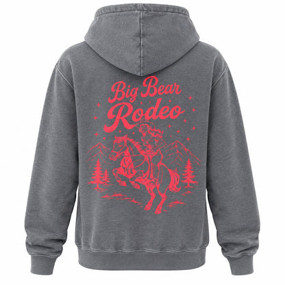 A dark gray hooded sweatshirt shown from the back, featuring a large red graphic print of a cowboy riding a bucking horse with the words 'Big Bear Rodeo' and small mountain and tree silhouettes.