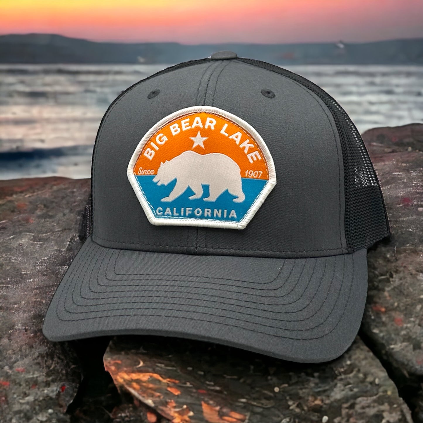 Orange and blue themed logo with a bear on a grey trucker hat