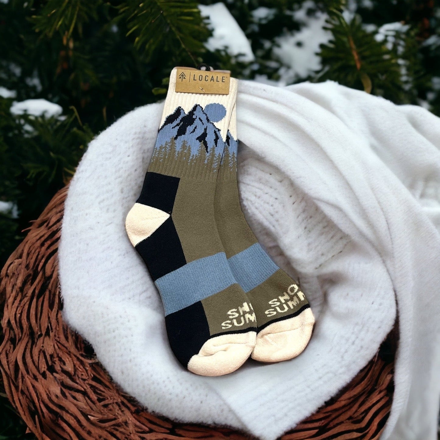 Blue, forest green, black, and white Locale Snow Summit sock with mountain forest design.