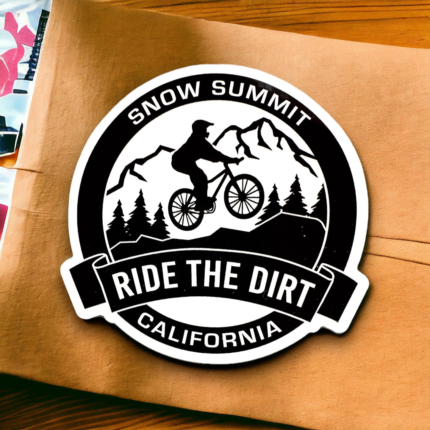 Snow Summit CA Ride the Dirt black and white sticker with a mountain biker on trail lined with trees and mountain design