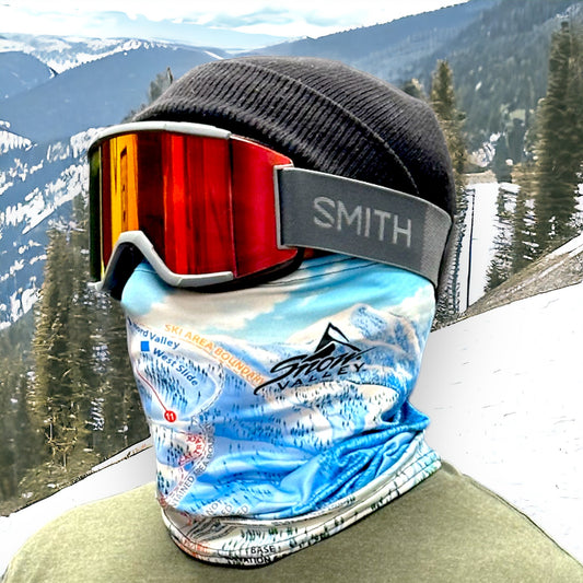 Rider in black beanie, Smith goggles, and a Snow Valley winter trail map neck gaiter