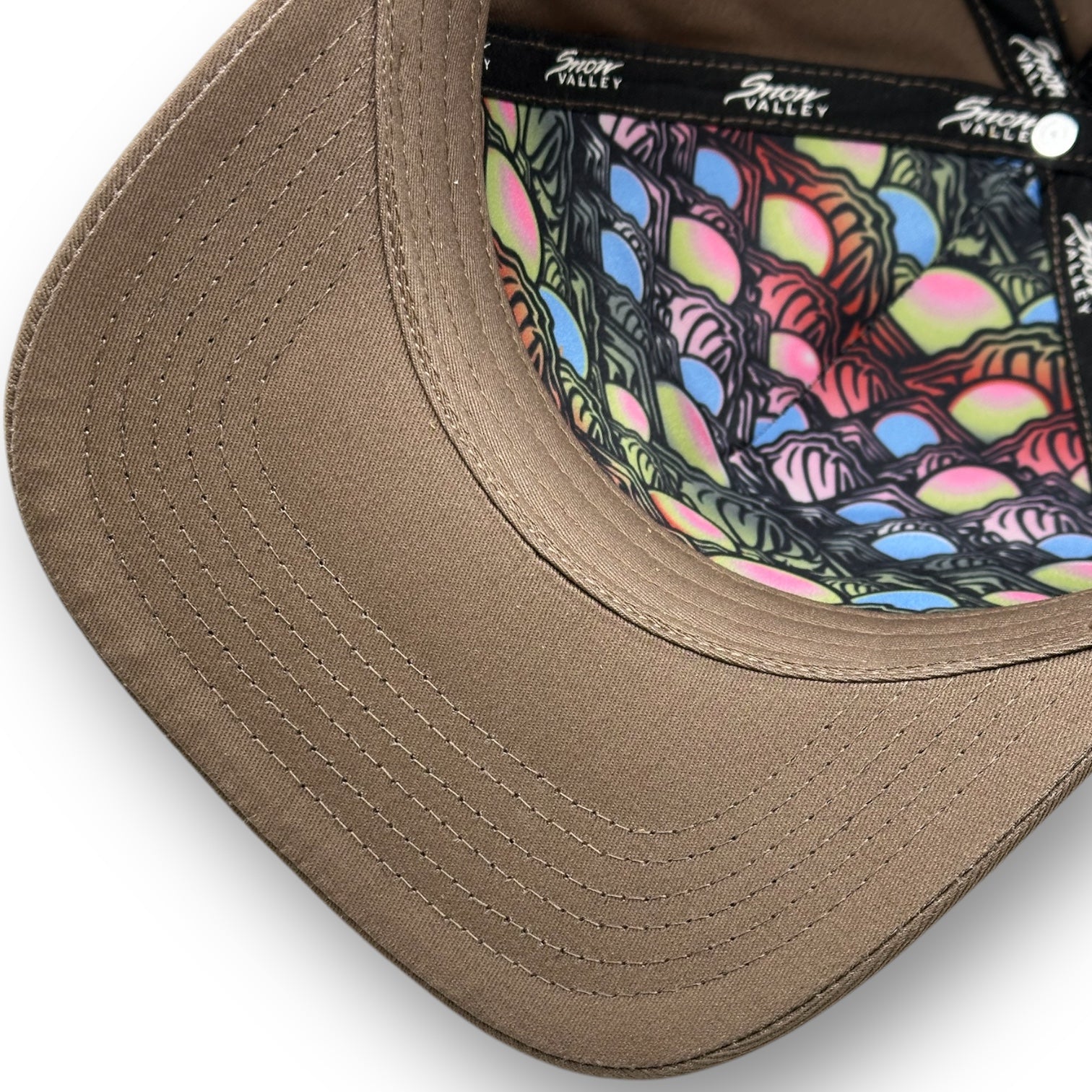 The underside of a Snow Valley hat with beige color and colorful fish scale pattern