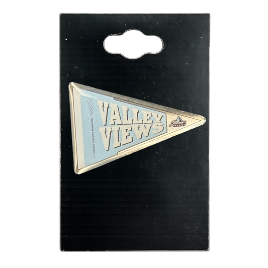 A triangular blue and white 'VALLEY VIEWS' enamel pin on a black display card with a hanging tab.