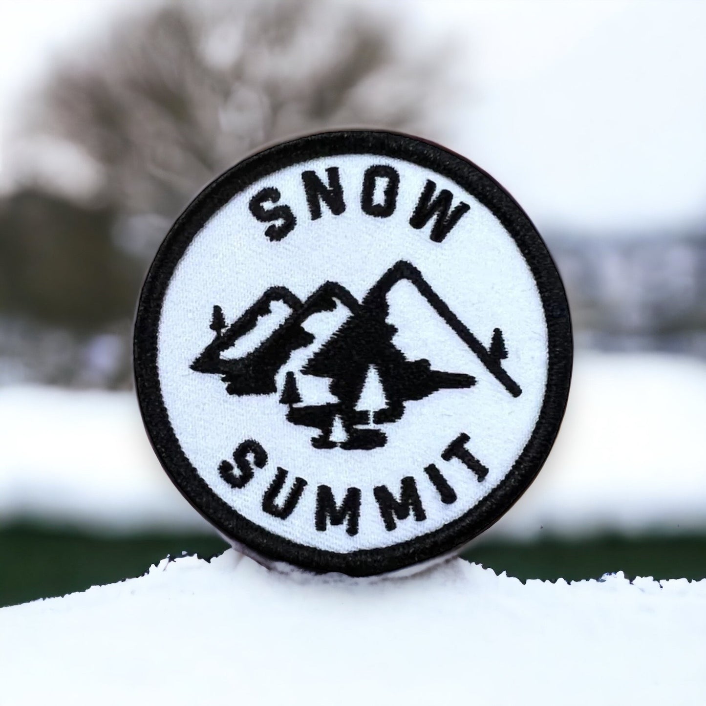 White patch with a snow summit logo and mountain stiched on it
