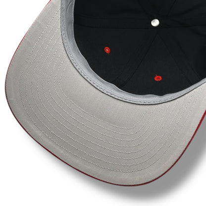 The gray under brim of a black hat, with red brim and black lining.